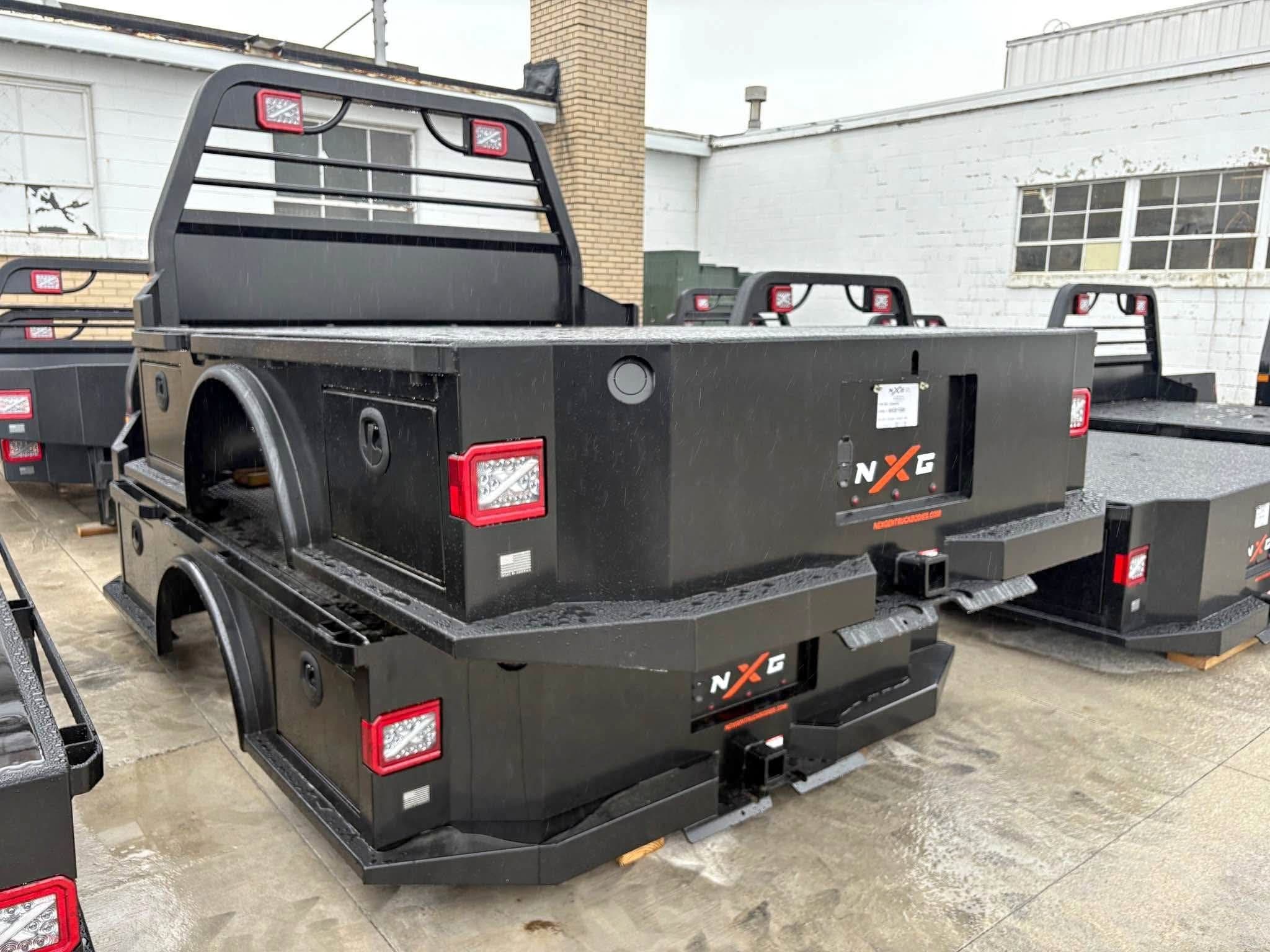 NXG XSD steel skirted flatbed in black, rear three-quarter view showing the skirted side toolboxes, fender wells, and built-in headache rack